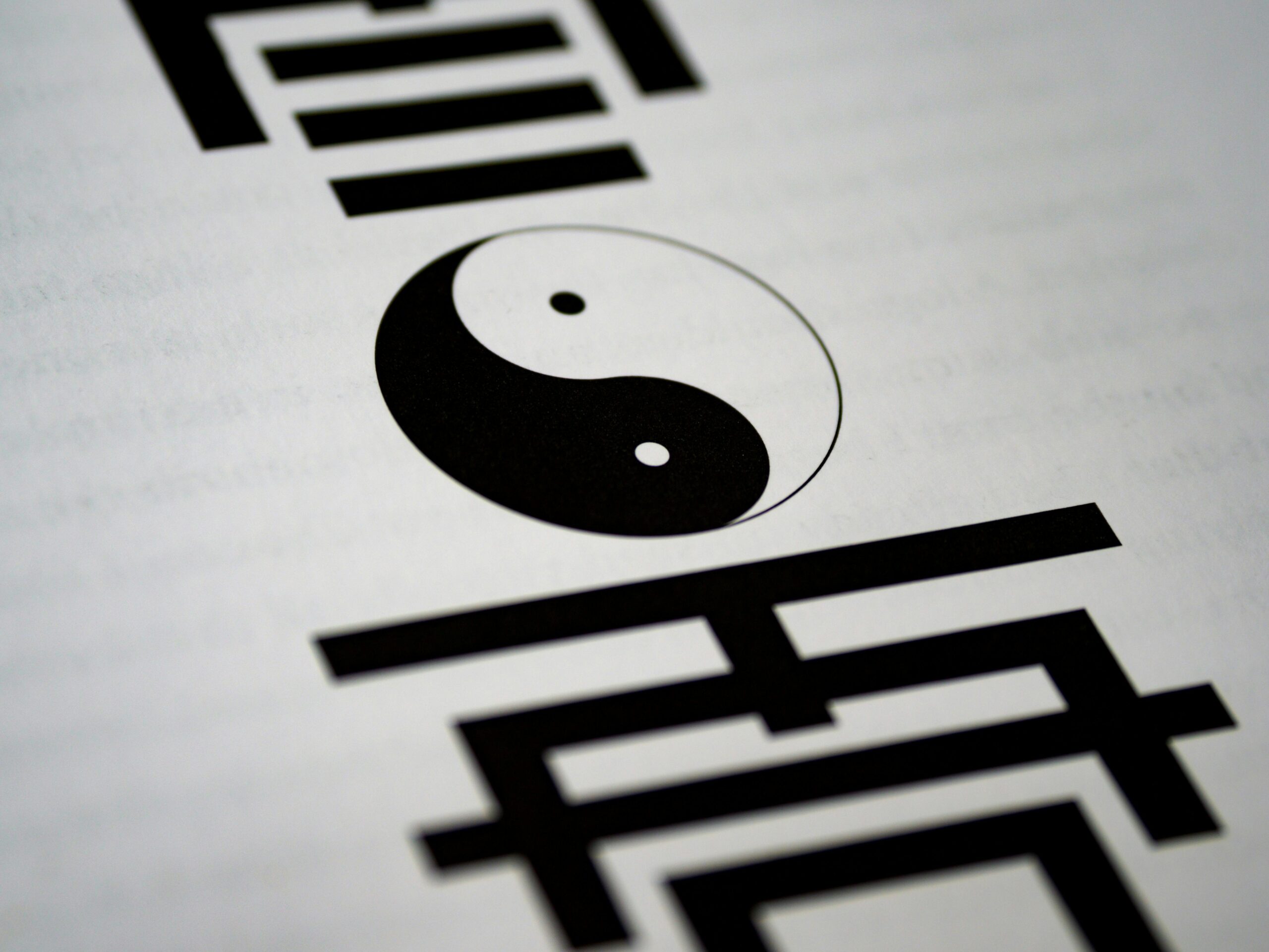 Artistic close-up of yin-yang symbol with Chinese calligraphy on paper.